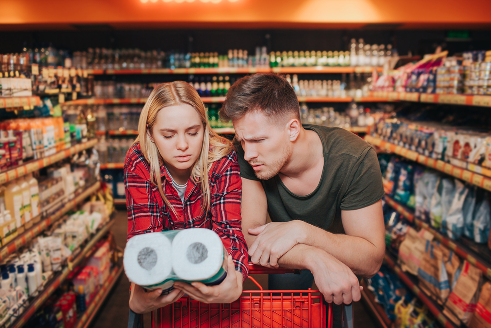 photo-of-couple-looking-at-straw-toilet-paper-with-confused-expression-in-supermarket-increased-prices